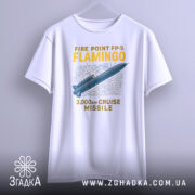 Футболка фламіго білого кольору, підвішена на вішалці, ракурс спереду, фон світло-сірий, принт з малюнком ракети та текстом "FIRE POINT FP-5 FLAMINGO 3,000km CRUISE MISSILE" у жовтому та синьому кольорах.