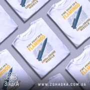Футболка фламіго білого кольору, зображена на манекені, ракурс спереду, фон світло-сірий, принт з малюнком ракети та текстом "FIRE POINT FP-5 FLAMINGO 3,000km CRUISE MISSILE" у жовтому та синьому кольорах.
