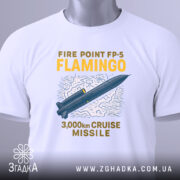 Футболка фламіго білого кольору, складена на поверхні, ракурс зверху, фон світло-сірий, принт з малюнком ракети та текстом "FIRE POINT FP-5 FLAMINGO 3,000km CRUISE MISSILE" у жовтому та синьому кольорах, з етикеткою зеленого кольору.