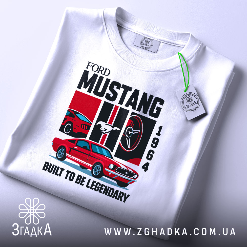 Футболка Ford Mustang класика, біла, складена на поверхні, фон світло-сірий, принт з червоним автомобілем Ford Mustang 1964, логотипом Ford, написом 'BUILT TO BE LEGENDARY', з етикеткою на рукаві.