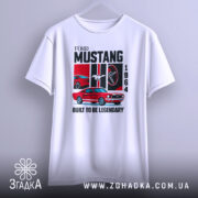 Футболка Ford Mustang класика, біла, підвішена на вішалці, фон світло-сірий, принт з червоним автомобілем Ford Mustang 1964, логотипом Ford, написом 'BUILT TO BE LEGENDARY'.