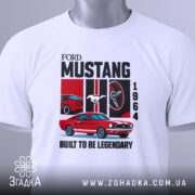 Футболка Ford Mustang класика, біла, складена на поверхні, фон світло-сірий, принт з червоним автомобілем Ford Mustang 1964, логотипом Ford, написом 'BUILT TO BE LEGENDARY', з етикеткою на рукаві.