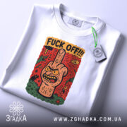 Футболка fuck off стиль, біла, зображена зверху, складена, фон світло-сірий, принт з малюнком руки з середнім пальцем, червоний фон з елементами зеленого та жовтого, на ярлику зелена стрічка.