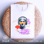 Футболка Girls Rule Art білого кольору, складена на кошику, зображена з верхнього ракурсу, фон світло-сірий, принт з графічним зображенням статуї з навушниками та сонцезахисними окулярами, кольори принта: червоний, фіолетовий, жовтий, чорний.