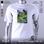 Футболка геть з України, біла, зображена на манекені, фон нейтральний, принт зображує жінку та істоту, що працюють на городі, текст на принті: 'Геть з України, москаль некрасивий!'