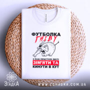 Футболка гніву білого кольору, зображена на плетеній основі, фон світлий, принт з малюнком гніву слона та текстом червоного і чорного кольору, вид з верхньої частини.