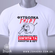 Футболка гніву білого кольору, зображена на столі, ракурс зверху, фон світлий, принт з малюнком гніву слона та текстом червоного і чорного кольору, на футболці є етикетка.
