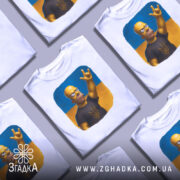 Футболка гомер з тризубом, біла, зображена на манекені, фон світло-сірий, принт з гомером у чорній футболці з тризубом на жовто-блакитному фоні.