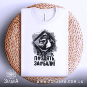 Футболка горила антинахабство, біла, зображена зверху на плетеній основі, фон світло-сірий, принт з горилою та текстом чорного кольору.