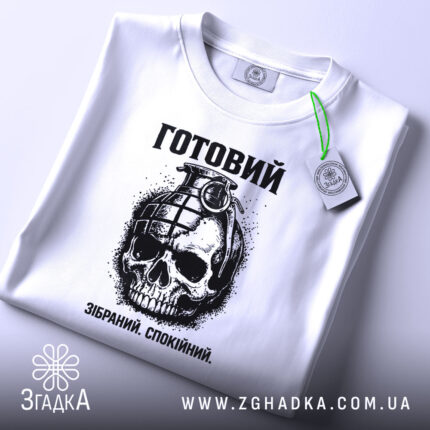Футболка готовий до дій, біла, зображена зверху, на ній підвішений етикет, фон світло-сірий, принт з черепом та гранатою, текст "Готовий. Зібраний. Спокійний." під малюнком.