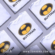 Футболка гумор буттмен, біла, зображена з правого ракурсу на манекені, фон світло-сірий, принт з жовтим і чорним логотипом у формі кажана з написом 'BUTTMAN'.