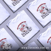 Футболка гусак з характером, біла, зображена на манекені з правого ракурсу, фон світло-сірий, принт з гусаком, який тримає мозок, текст "HEY, YOU DROPPED THIS STUPID" в яскравих кольорах.