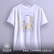 Футболка гуси гумор, біла, підвішена на вішалці, фон світло-сірий, принт з жовтими гусячими головами та текстом 'what?' у верхній частині.