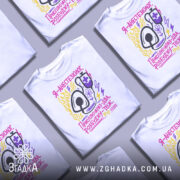 Футболка я анестезіолог, білого кольору, зображена з фронтального ракурсу на манекені, фон світло-сірий, принт містить малюнок стетоскопа та текст у яскравих кольорах: жовтому, рожевому та фіолетовому.