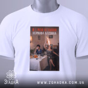 Футболка я і нерви. Біла футболка, складена на столі, з принтом, що зображує двох жінок, одна з яких підносить пляшку з вогнем, фон - затишна кімната з меблями та столом, заставленим їжею.