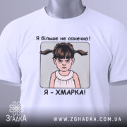 Футболка я хмарка, біла, складена на столі, фон світло-сірий, принт з дівчинкою з двома хвостиками та написом 'Я більше не сонечко! Я - ХМАРКА!', на футболці є етикетка з зеленим шнурком.