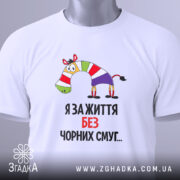 Футболка я за життя, білого кольору, складена на поверхні, фон світло-сірий, принт з зеброю в смугастому одязі та написом "Я за життя без чорних смуг...", на комірці видна етикетка.