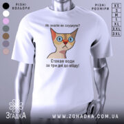 Футболка як швидко схуднути. Біла футболка з принтом, на якому зображена кішка з великими блакитними очима та червоним носом. Принт містить текст: 'Не знаєте як схуднути? Стакан води за три дні до обіду!' Фон нейтральний, без додаткових елементів.