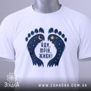 Футболка йди мрій живи, біла, зображена зверху, фон світло-сірий, принт у вигляді слідів з зірками та місяцем, на комірці є етикетка.