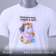 Футболка єдинорог нормальна жінка, біла, складена на столі, фон світло-сірий, принт з єдинорогом, що тримає ніж, текст зверху: 'Нормальна жінка – нудьга в сім'ї', на футболці зелена етикетка.
