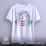 Футболка єдинороги білого кольору, підвішена на вішалці, фон світло-сірий, принт з веселкою та єдинорогами, текст "ЧАРІВНА НА ВСЮ ГОЛОВУ" в чорному кольорі.