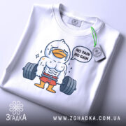 Футболка качок тренування, біла, зображена зверху, фон світло-сірий, принт з качком у спортивному костюмі, що піднімає важкі гирі, текст 'NO PAIN NO GAIN', на футболці є етикетка з зеленим шнурком.