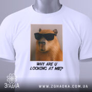 Футболка капібара з жартом, біла, складена на столі, фон світлий, принт з капібарами в окулярах та текстом "WHY ARE U LOOKING AT ME?" під ним, з етикеткою на рукаві.