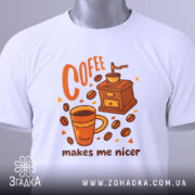 Футболка кавовий характер, біла, зображена зверху, фон світлий, принт з чашкою кави, кавомолкою та написом 'makes me nicer', з етикеткою на рукаві.