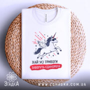 Футболка хай тривоги, біла, зображена зверху на плетеній основі, фон білий, принт з єдинорогом у сонцезахисних окулярах, з крилами та червоними лініями навколо.