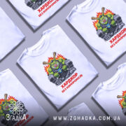 Футболка хардкор без компромісів, біла, зображена на манекені, фон нейтральний, принт з зеленим персонажем, що тримає гантелі, з червоним написом 'ХАРДКОР БЕЗ КОМПРОМІСІВ'.