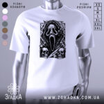 Футболка хорор скрім, біла футболка на манекені, з принтом чорного кольору, що зображує маску з фільму жахів, на фоні світло-сірого кольору, деталі принта включають черепи та елементи, що нагадують про жахи.