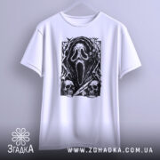 Футболка хорор скрім, біла футболка, підвішена на вішалці, з принтом чорного кольору, що зображує маску з фільму жахів, на фоні світло-сірого кольору, деталі принта включають черепи та елементи, що нагадують про жахи.