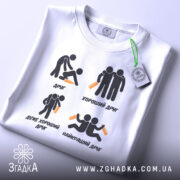 Футболка хороший друг, біла, зображена зверху, фон світло-сірий, принт з чотирма іконками та текстом про друзів, з зеленим ярликом.