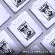 Футболка хто тут головний. Біла футболка на манекені, з принтом чорного кольору, що зображує персонажа з окулярами, який вказує пальцем. Фон світло-сірий, деталі принта чітко видимі.