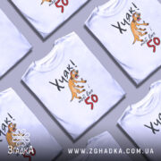 Футболка Хуяк тобі 50, біла, зображена з фронтального ракурсу, на манекені, фон світло-сірий, принт з жовтим собакою, що виглядає здивованою, текст чорний і червоний.