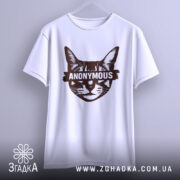 Футболка кіт анонімус білого кольору, підвішена на вішалці, фон світло-сірий, принт зображає кота з написом 'ANONYMOUS' у коричневому кольорі, футболка має класичний крій.