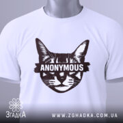 Футболка кіт анонімус білого кольору, складена на поверхні, фон світло-сірий, принт зображає кота з написом 'ANONYMOUS' у коричневому кольорі, на футболці є етикетка з зеленим шнурком.