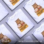 Футболка кіт і кава, біла, зображена з фронтального ракурсу на манекені, фон світло-сірий, принт з котом, який тримає пончик і чашку кави, текст на жовтому фоні: 'половину проблем в житті вирішує кофе'.