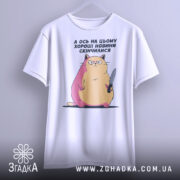 Футболка кіт погані новини, біла, зображена на манекені, фон світло-сірий, принт з котом з ножем, з рожевими і жовтими відтінками.