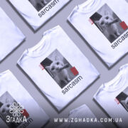 Футболка кіт сарказм, біла, зображена на манекені, фон світло-сірий, принт з чорним котом, який тримає сигару, з червоними смужками.