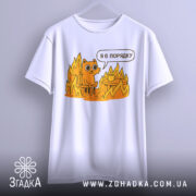 Футболка кіт це нормально. Біла футболка, підвішена на вішалці, з принтом оранжевого кота, що сидить на стільці серед вогню, з текстом 'Я в порядку'. Фон світло-сірий, деталі принта яскраві.