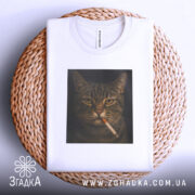 Футболка кіт з цигаркою, біла, складена на плетеній кошику, фон світло-сірий, принт з котом, що курить, з чіткими деталями.