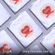 Футболка кохайтеся коли сваряться, біла, зображена на манекені, фон світло-сірий, принт червоного серця з жовтими променями та написом.