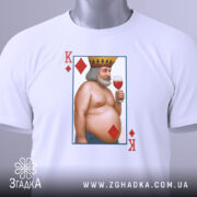 Футболка король черви, біла, складена на поверхні, фон світло-сірий, принт з ілюстрацією короля червів, який тримає келих з вином, з короною на голові, з червоними ромбами, на футболці є етикетка.