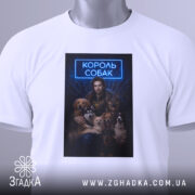 Футболка король собак, біла, складена на поверхні, фон світлий, принт з зображенням чоловіка з собаками, текст "КОРОЛЬ СОБАК" у неоновому стилі, на футболці є етикетка.