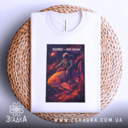 Футболка космос мій океан, біла, складена на плетеній кошику, фон світлий, принт з космонавтом на рибі в космосі, яскраві кольори принта.