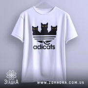 Футболка котячий стиль adicats, біла, підвішена на вішалці, з фронтального ракурсу, фон світло-сірий, принт з трьома чорними котами з жовтими очима на смугастому фоні.