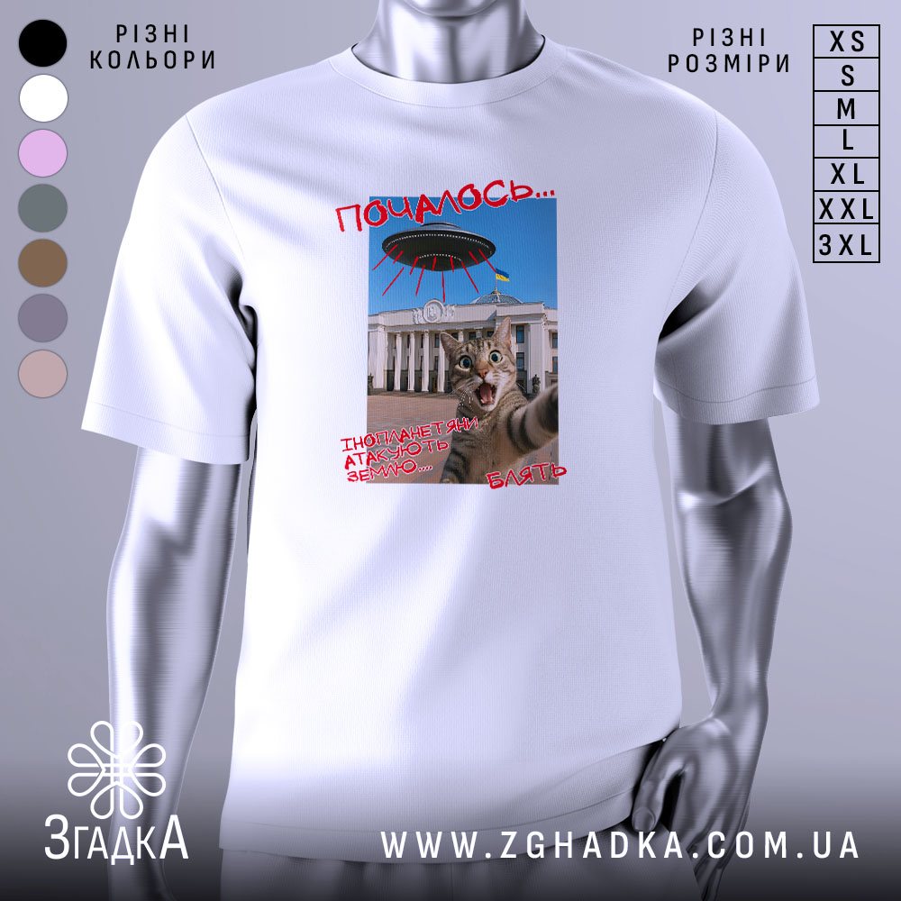 Futbolka Koty I Prybultsi Mem Pro Ataku 1 Футболка коти й прибульці, біла, зображена на манекені, фон нейтральний, принт з котом, що виглядає з-під літаючої тарілки, текст червоним кольором.
