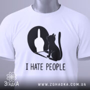 Футболка коти ненавиджу людей, біла, складена на плоскій поверхні, фон світло-сірий, принт чорного кольору з силуетом кота та жестом руки, на комірці є етикетка.