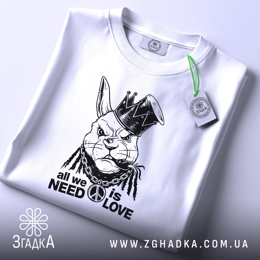 Футболка кролик панк, біла, зображена зверху, на фоні світлого градієнта. Принт зображає кролика в короні з дредами, з написом 'all we need is love' під ним, з етикеткою, що звисає.